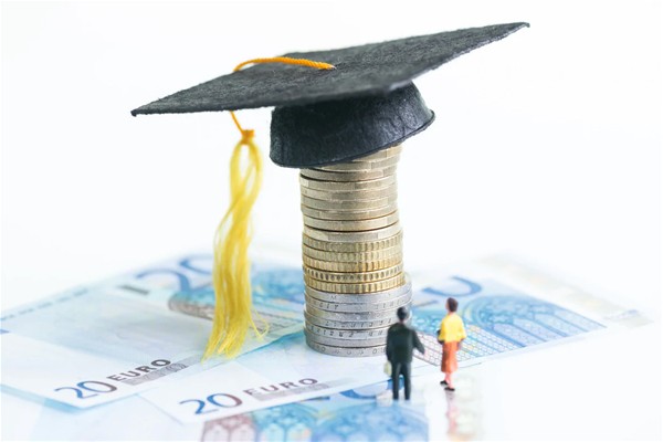 20 euro posati su un tavolo con sopra  uno sopra l'altro centesimi con alla fine appoggiato un cappello di carta nero di laurea