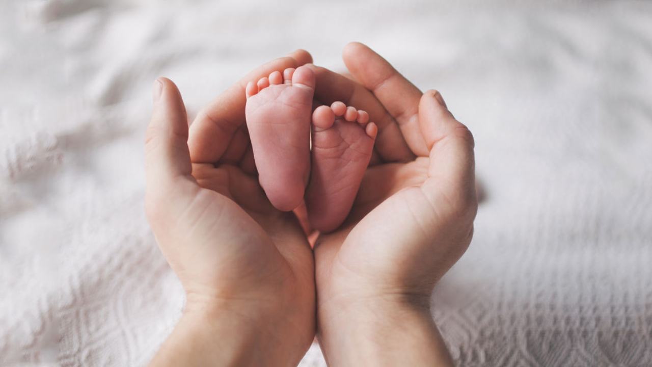 due mani di adulto che accolgono due piedini