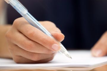 mano con penna che firma su foglio bianco 