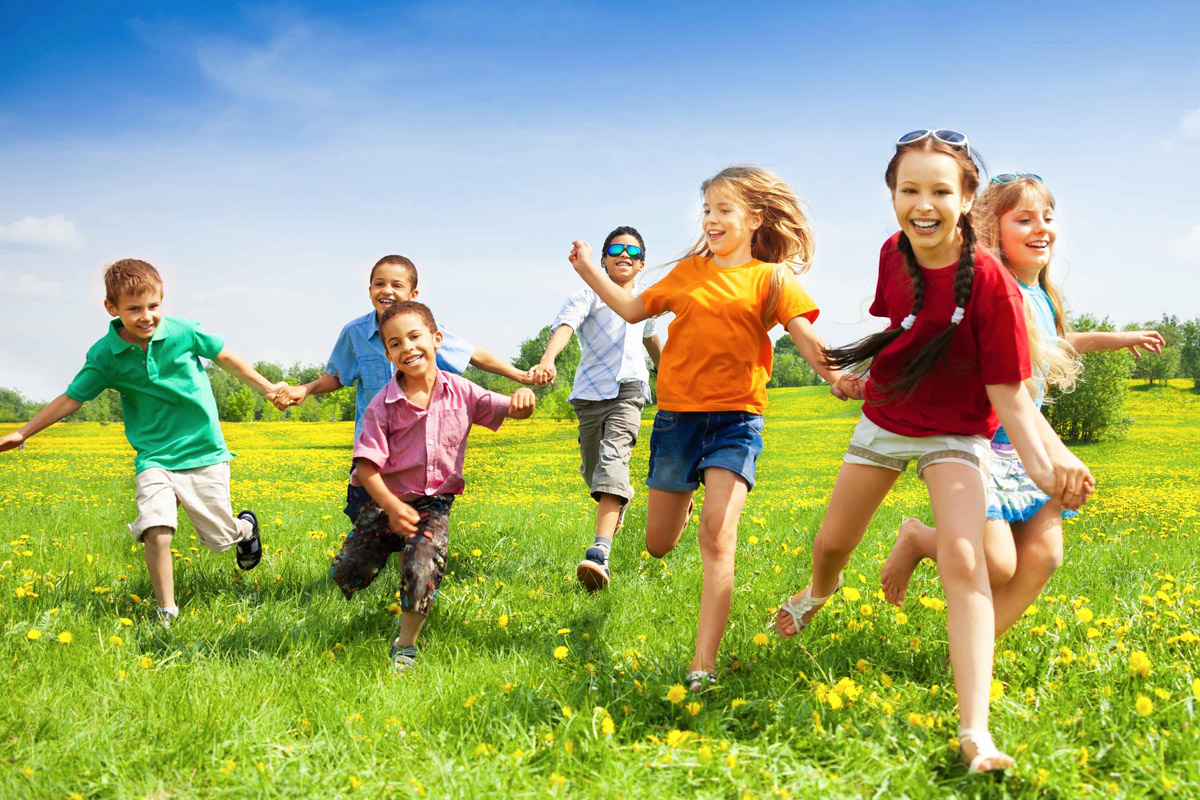 bambini che corrono in un giardino verde con fiori gialli