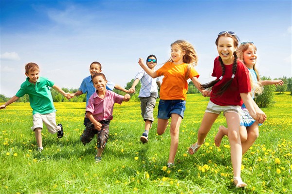 bambini che corrono in un giardino verde con fiori gialli