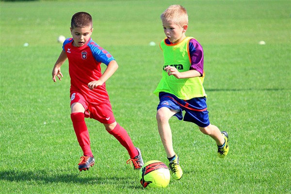 due bambini con completini sportivi che giocano a calcio 